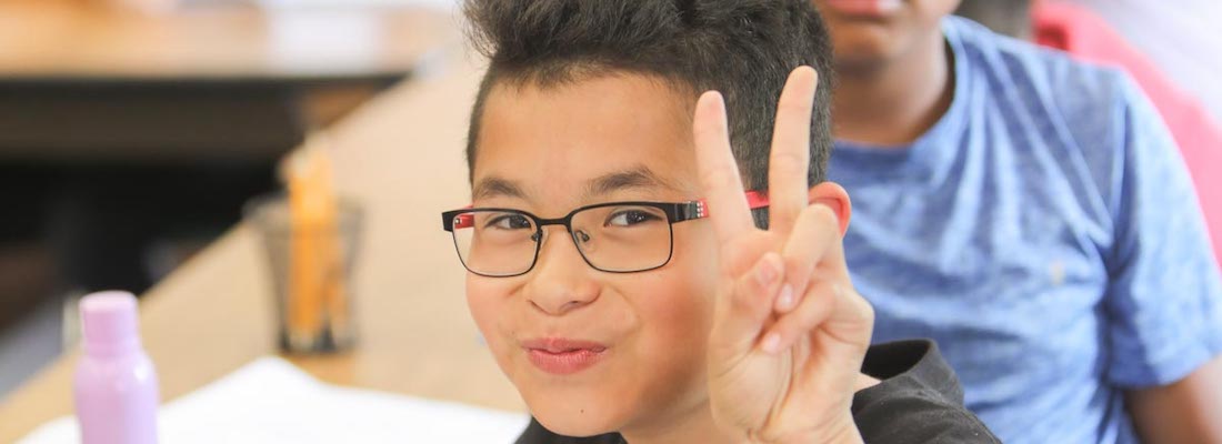 Student in class holding the peace sign