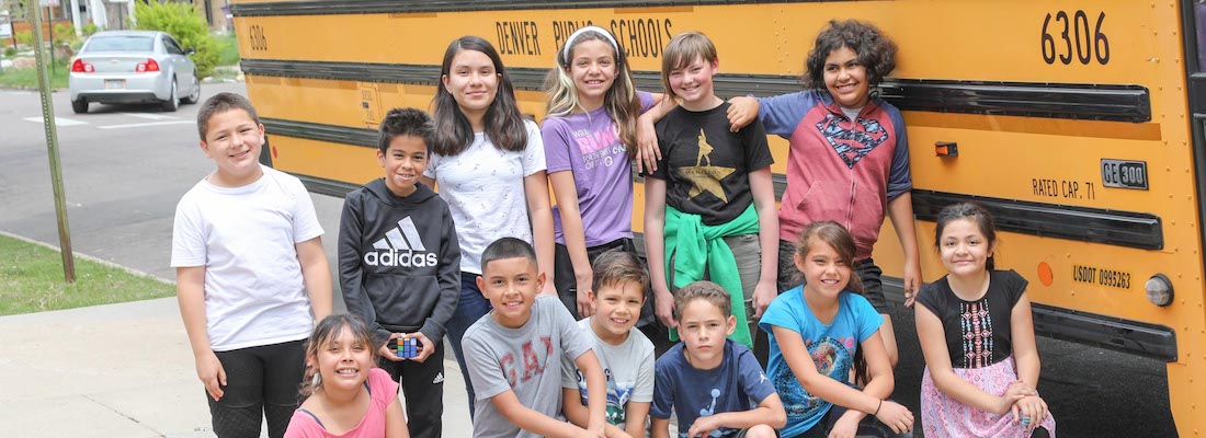 Group of students posing in front of a school bus