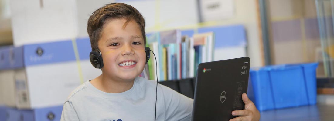 Student with headphones using laptop in class